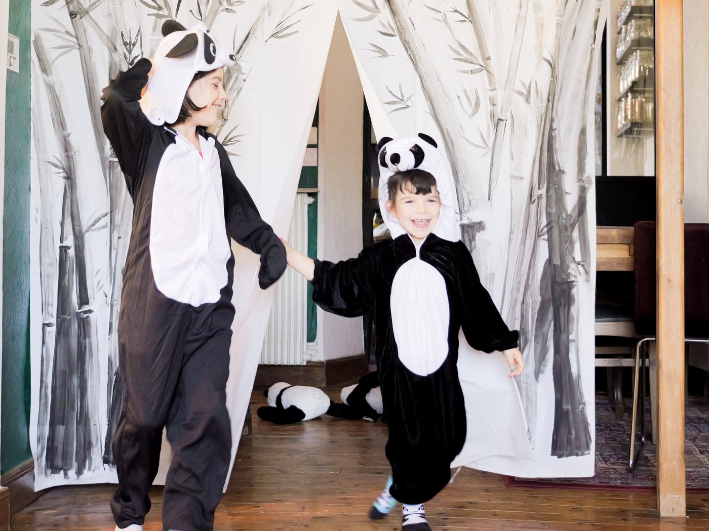 Dvoje dece u panda kostimima se poklanja ispred scenske zavese napravljene od ukrašene BJÄRSEN zavese za tuš.