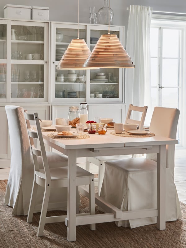 NORDVIKEN extendable table and chairs stand in a breakfast setting. Lit pendant lamps give warm lighting from above.