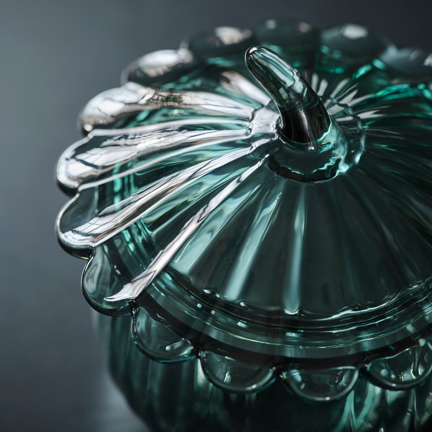 A close-up of the SNÖSISKA bowl with lid. The dark grey-green glass reflects the light in mesmerising way.