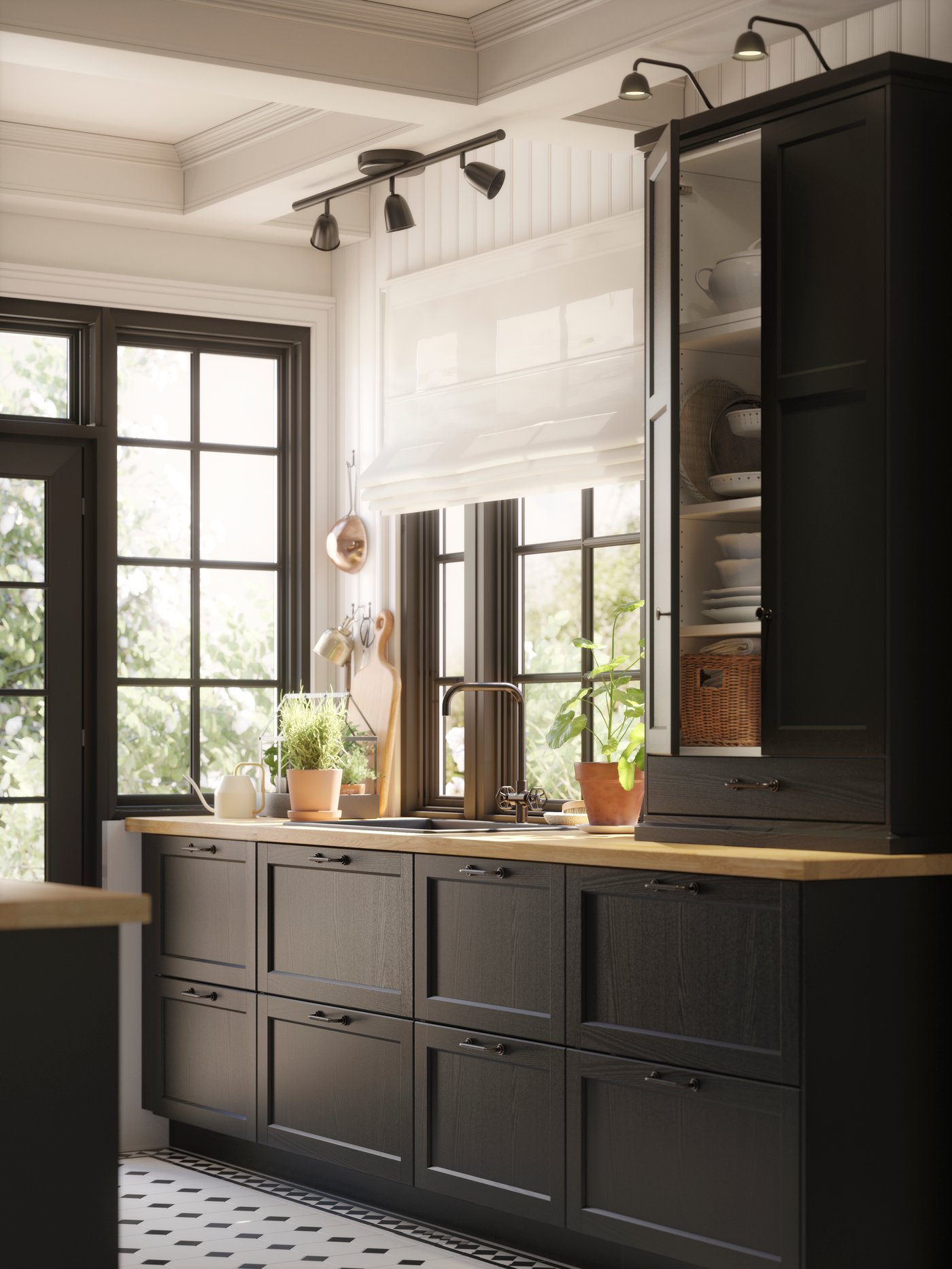 A big kitchen island with black-stained LERHYTTAN fronts and a wooden countertop has two big black pendant lamps above it.