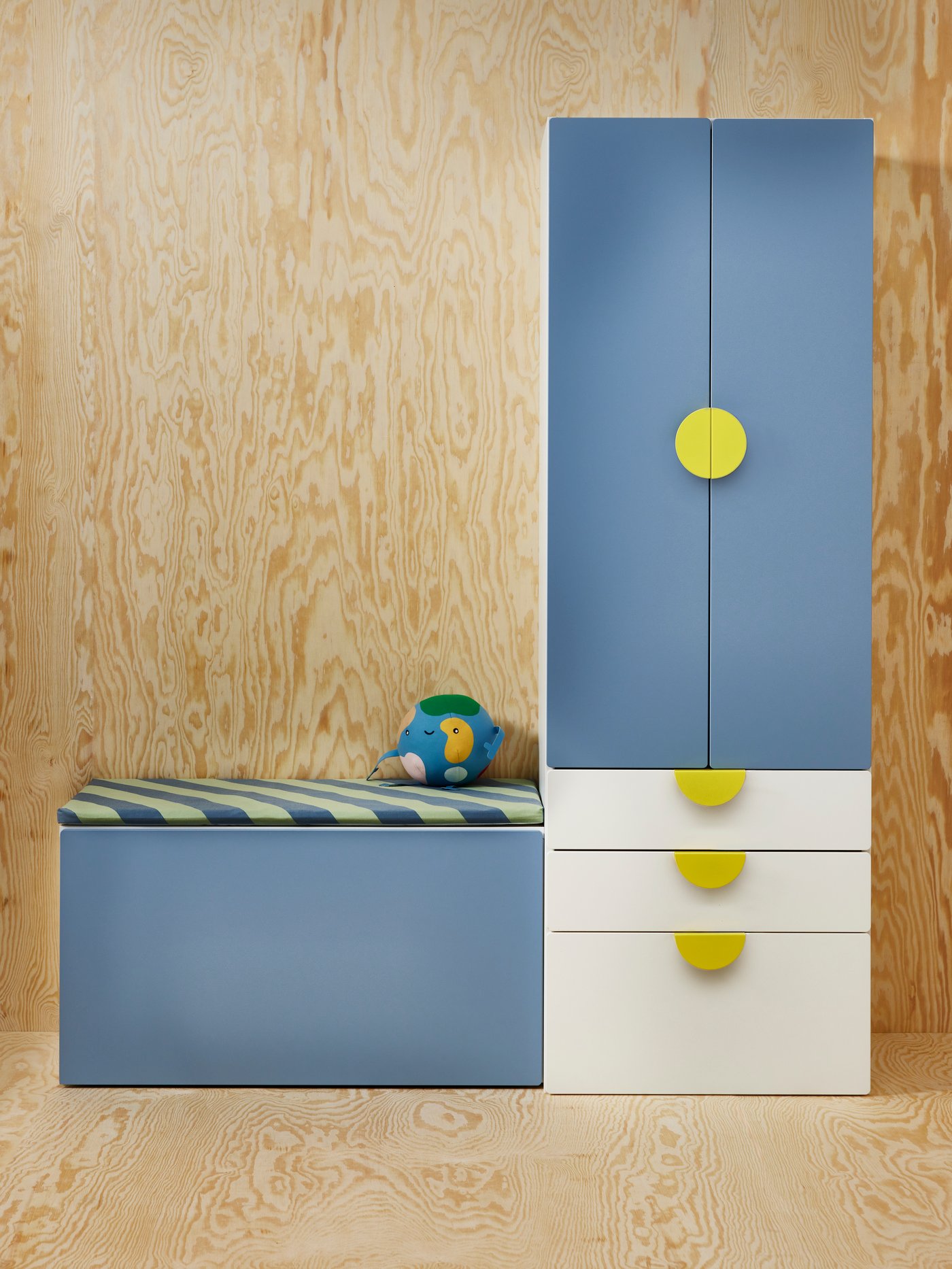 A white and blue SMÅSTAD cabinet with a yellow, semicircular BEGRIPA handle. Both the floor and walls are clad in light wood.