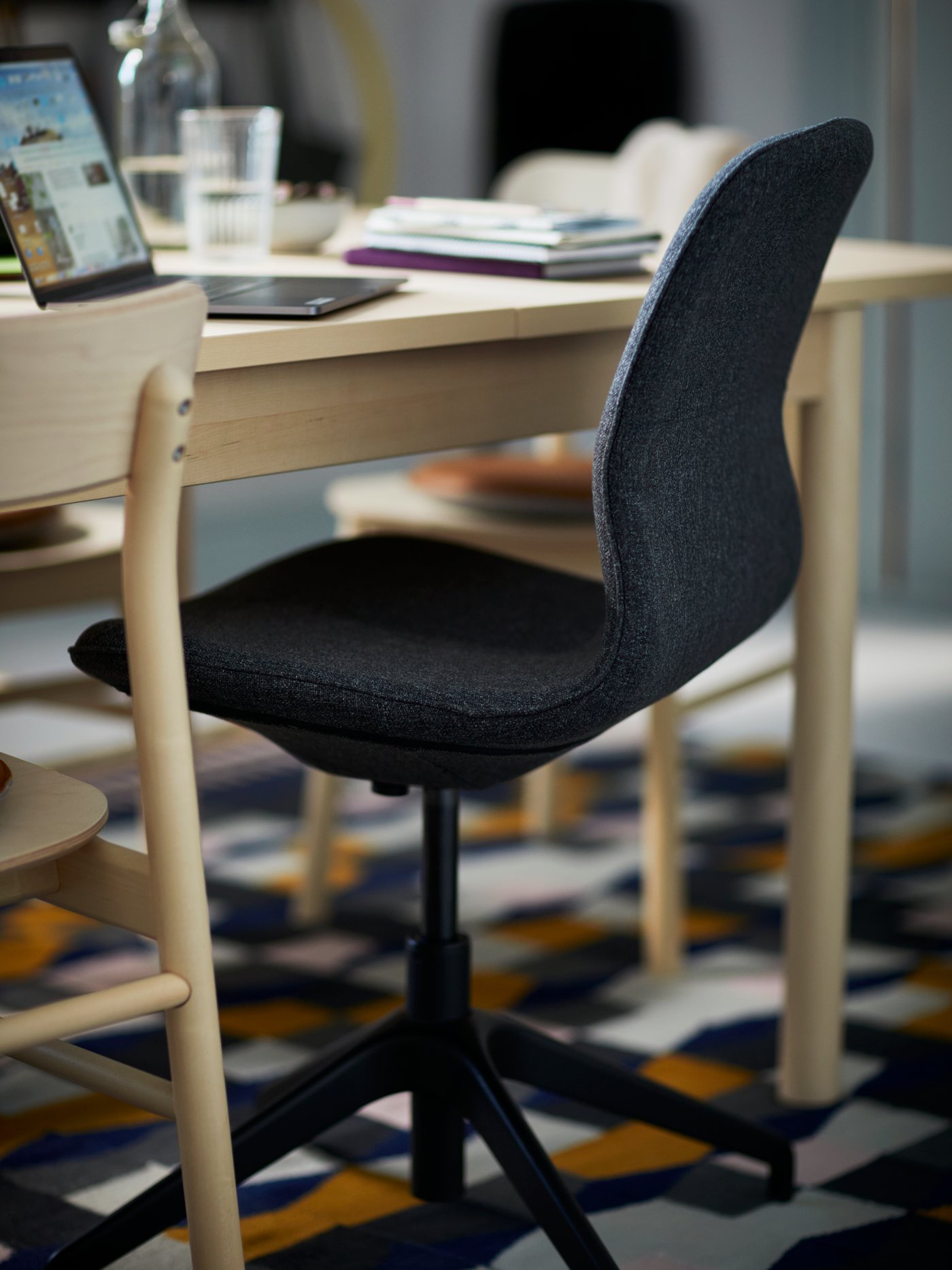 Una mesa de madera con una silla de escritorio ergonómica gris en el frente.