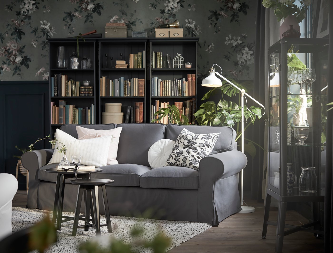 A grey EKTORP sofa with bright colored pillows in the center of a living room