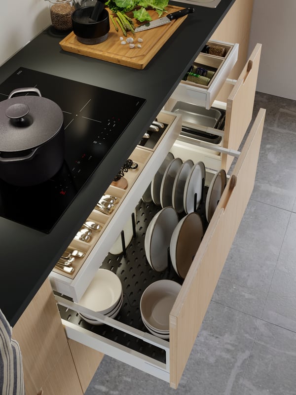 An open kitchen drawer with bamboo cutlery trays, and plates on an anthracite pegboard drawer organiser.
