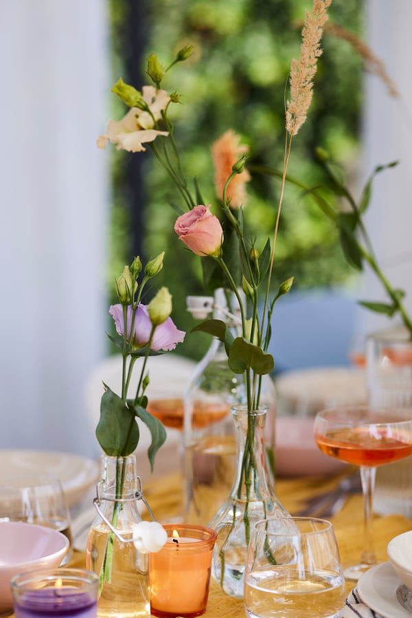 Close-up of a slender vase with a few flowers and grasses in it.