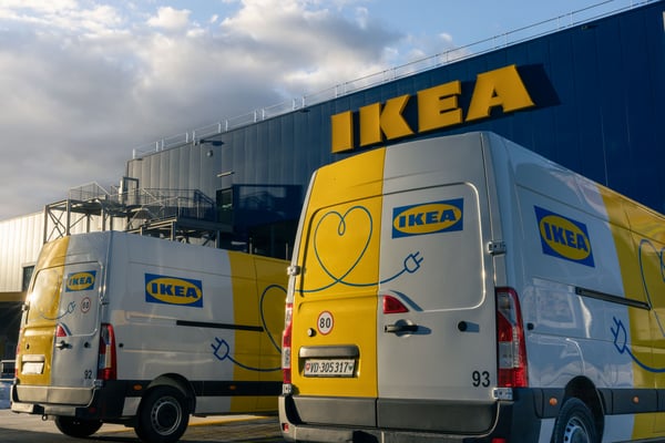 Two IKEA delivery EV trucks sit outside an IKEA store.
