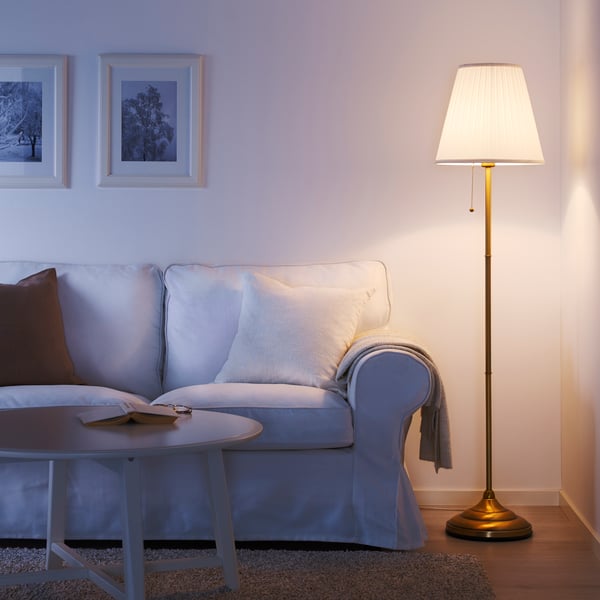 IKEA ÅRSTID brass/white floor lamp next to a two seater white sofa in the living room. 