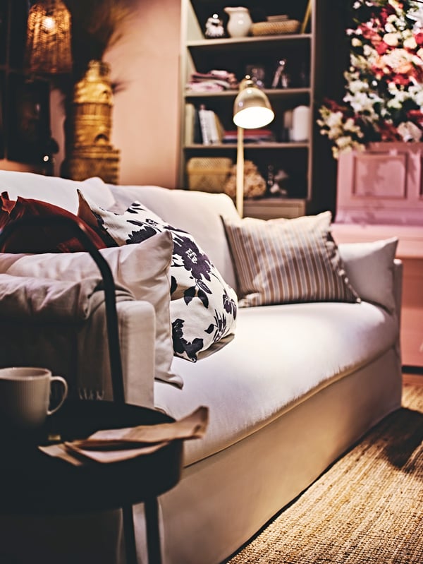 A natural HYLTARP 3-seat sofa with a long valance sheet stands in a rustic-style living room.