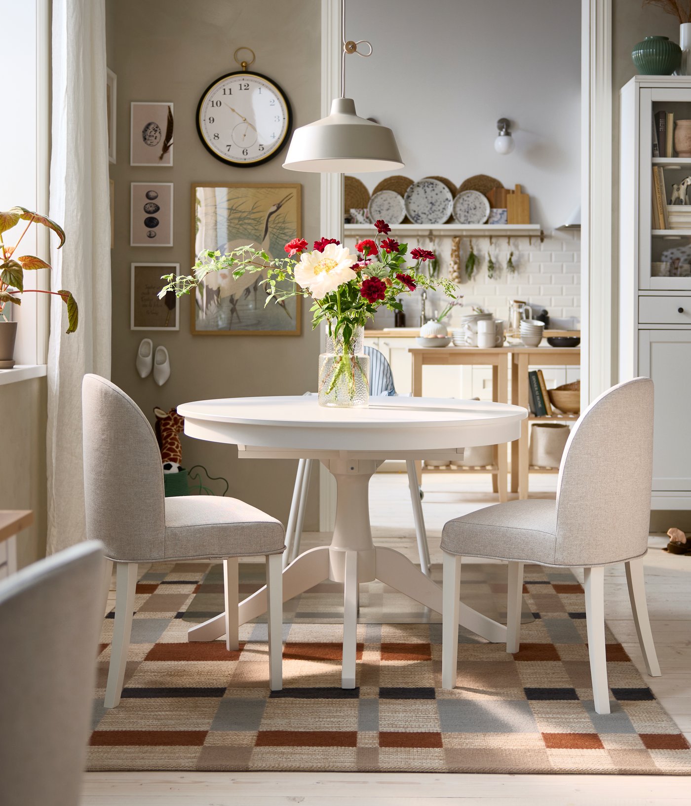 A bright dining area has a white ROSENTORP extendable table, two ROSENTORP chairs and an ANTILOP highchair with tray.
