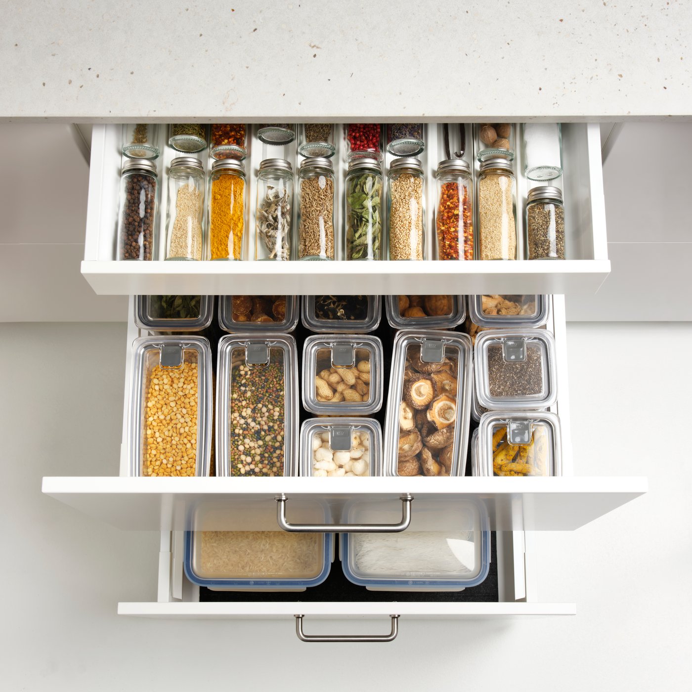 A kitchen drawer with spice jars and containers shows clear glass CITRONHAJ spice jars made from glass and stainless steel.