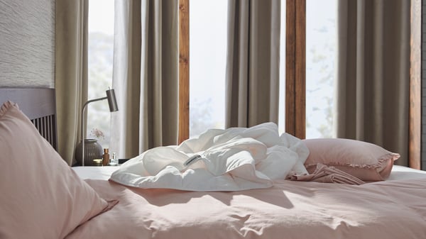 Dans une chambre à coucher, une couette blanche a été placée sur un lit avec des housses de couette roses.