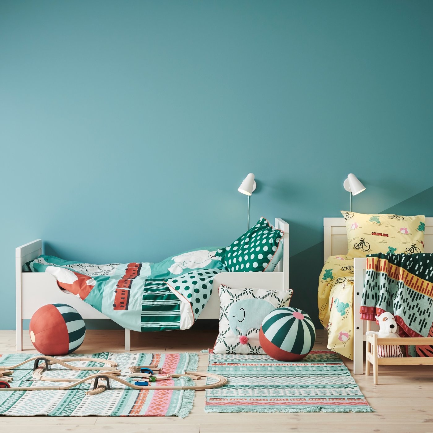 Habitación infantil en tonos verdosos donde destaca una cama extensible SUNDVIK blanca .Frente a la cama una serie de cojines y juguetes de niño