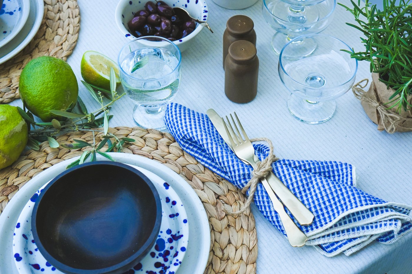 Gedeckter Tisch mit IKEA Silvereda Teller, NATTKLOT Besteck, blau-weisser Serviette, Limetten, Oliven. Perfekt für mediterrane Sommeressen.