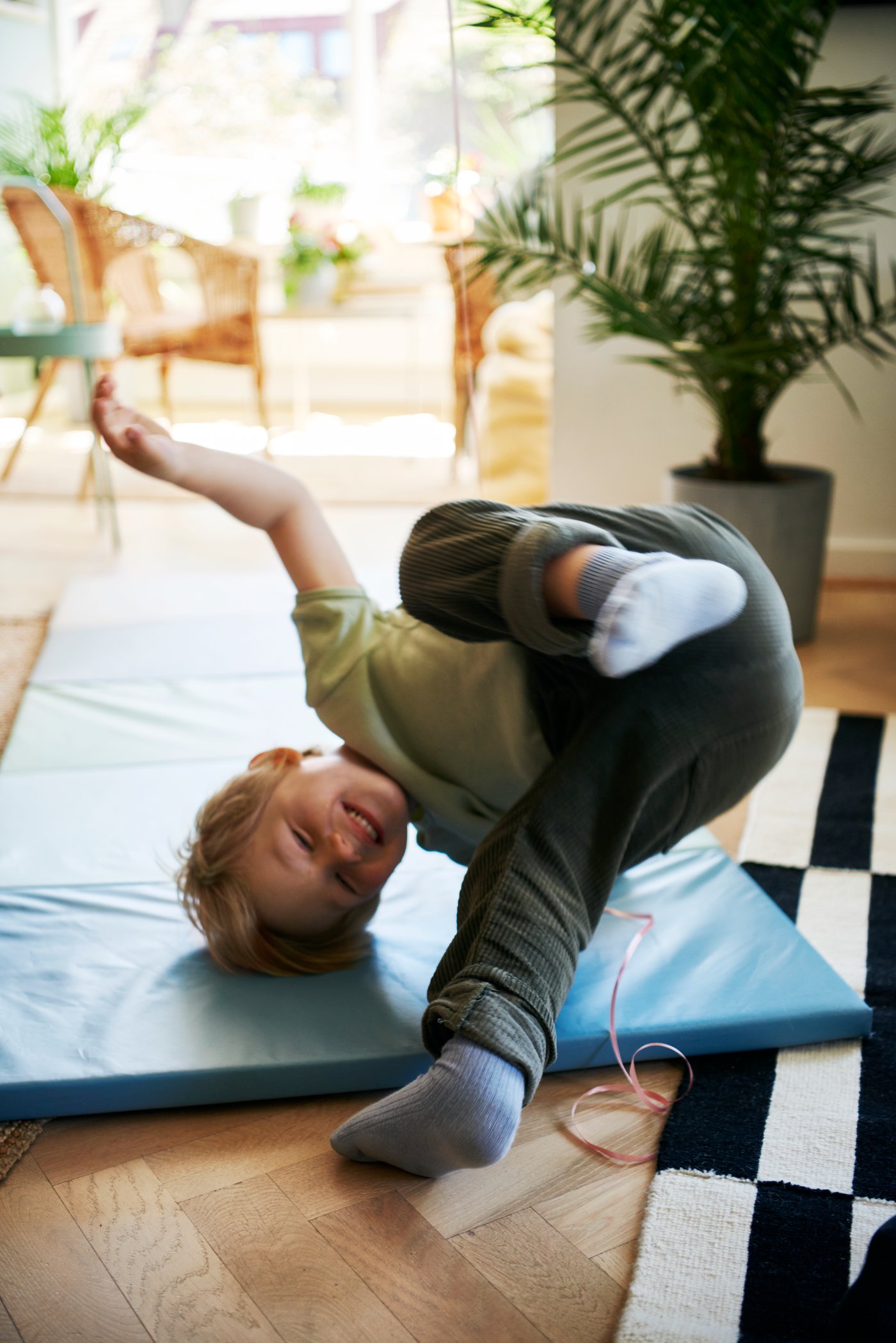 Jeune garçon faisant des roulades sur un tapis de jeu.