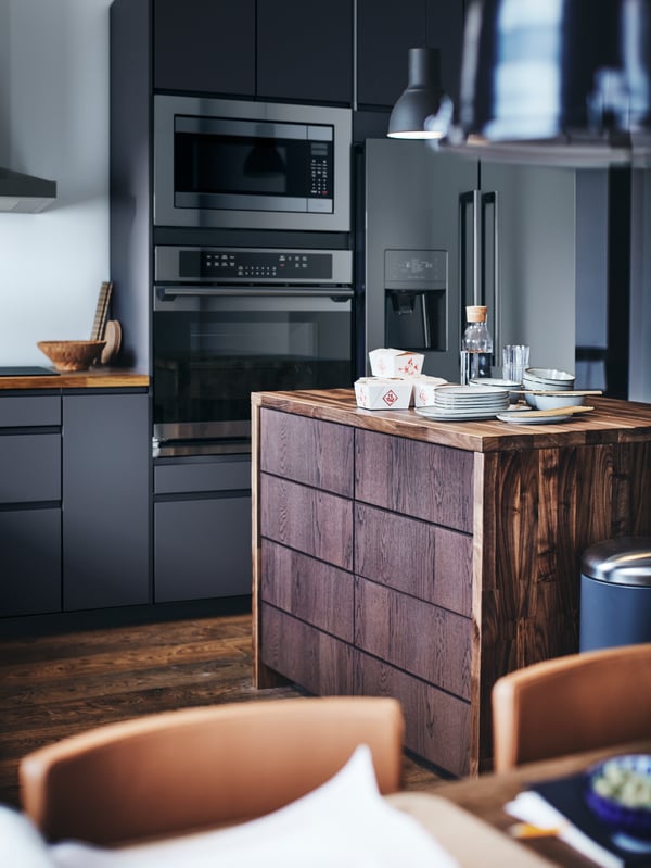 A SEKTION kitchen with a wooden kitchen island with plates and takeaway food containers on top.