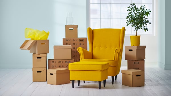 Un fauteuil IKEA entouré de cartons empilés. 