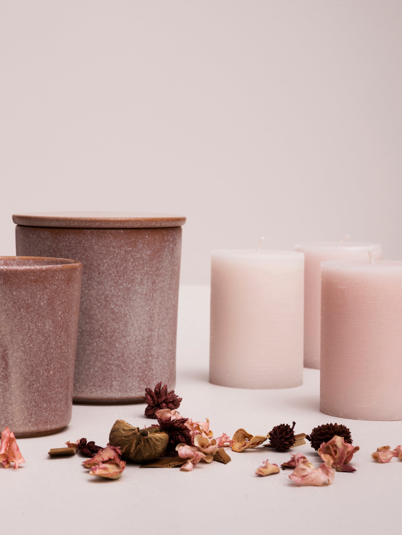 Une collection de bougies roses disposées sur une table à côté de pot-pourri.