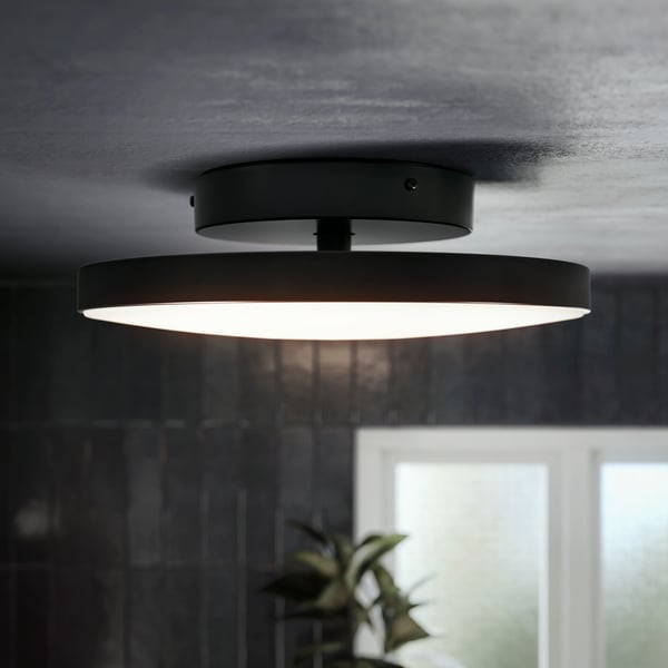 A dimmable matte black KABOMBA LED wall lamp is placed next to a round FAXÄLVEN mirror above a grey washbasin in a bathroom.