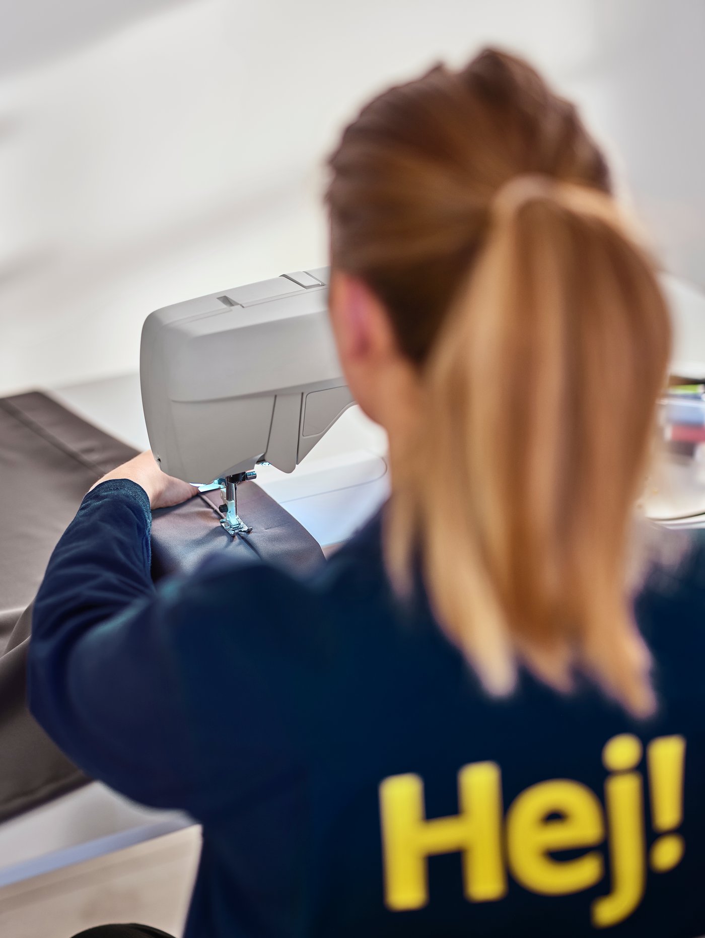 Zaposlena v podjetju IKEA uporablja šivalni stroj.