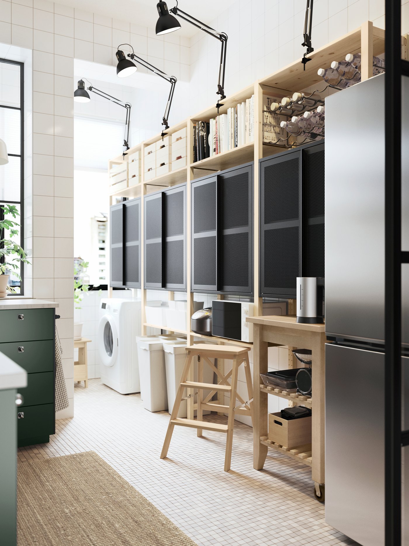 A pine IVAR shelving unit with two black mesh cabinets with doors and dark grey work lamps up top, plus a kitchen trolley.