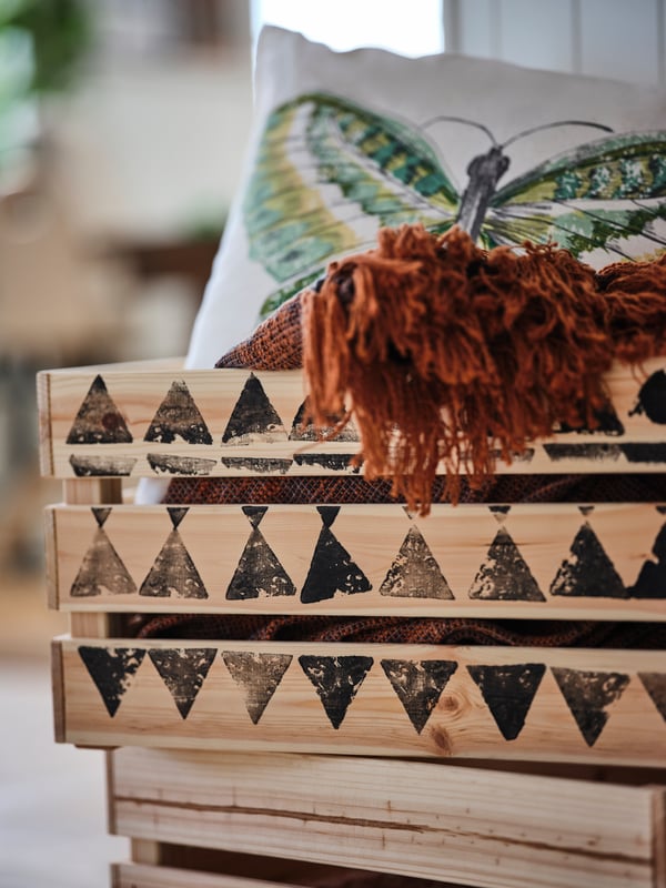 A pillow with a butterfly on it is in a KNAGGLIG box.
