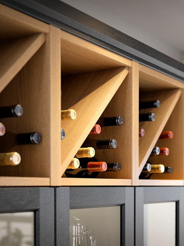 Three VADHOLMA wine shelves in stained ash with wine bottles inside.