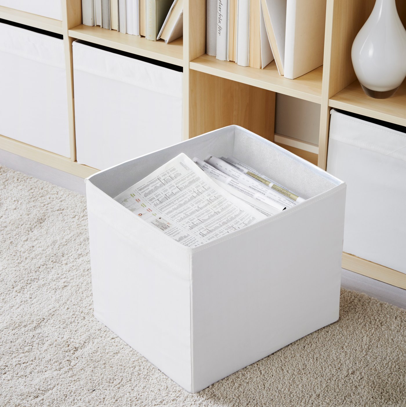 A white DRÖNA box in the living room in a KALLAX storage unit