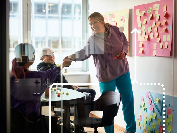 Group working in a small meeting room with colorful sticky notes covering the walls during a brainstorming session.