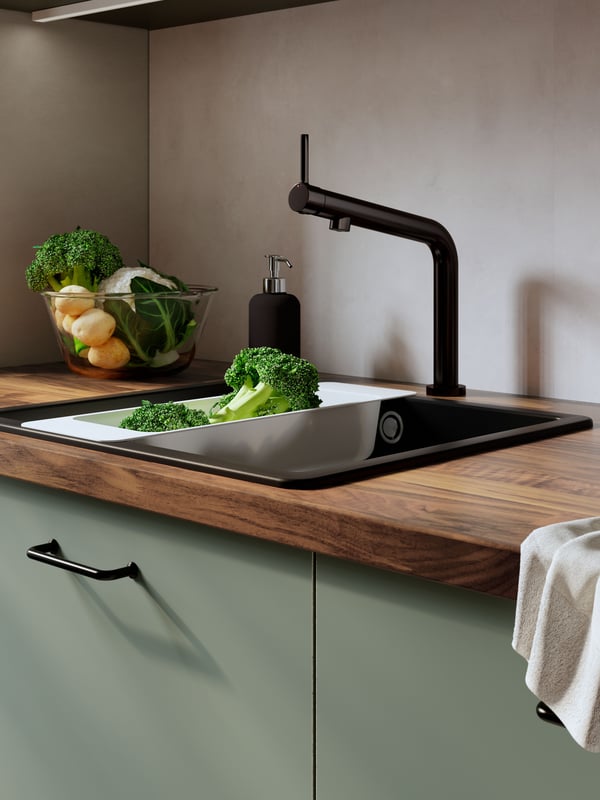 A kitchen setting featuring a KARLBY worktop, KILVISEN sink and METOD drawers in green.
