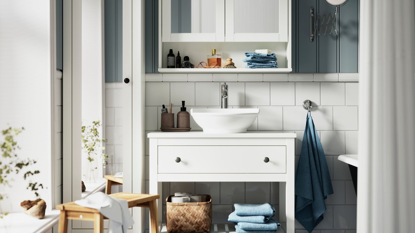 A white HEMNES wash-stand, with a white VÄSTERSJÖN countertop wash-basin, is placed underneath a HEMNES mirror cabinet.
