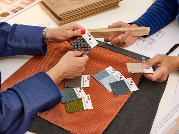 Une architecte d’intérieur IKEA montre à une cliente différents échantillons de tissu pour un projet d’aménagement.