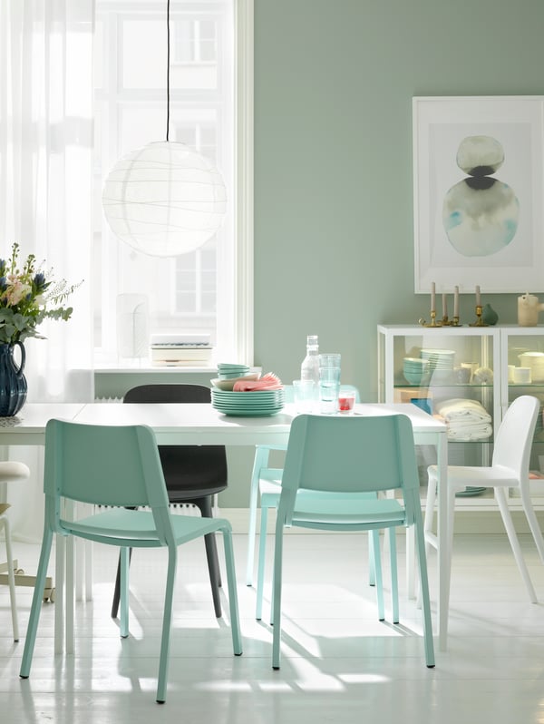 A dining area with a white MELLTORP table, a white REGOLIT lamp and assorted seating.