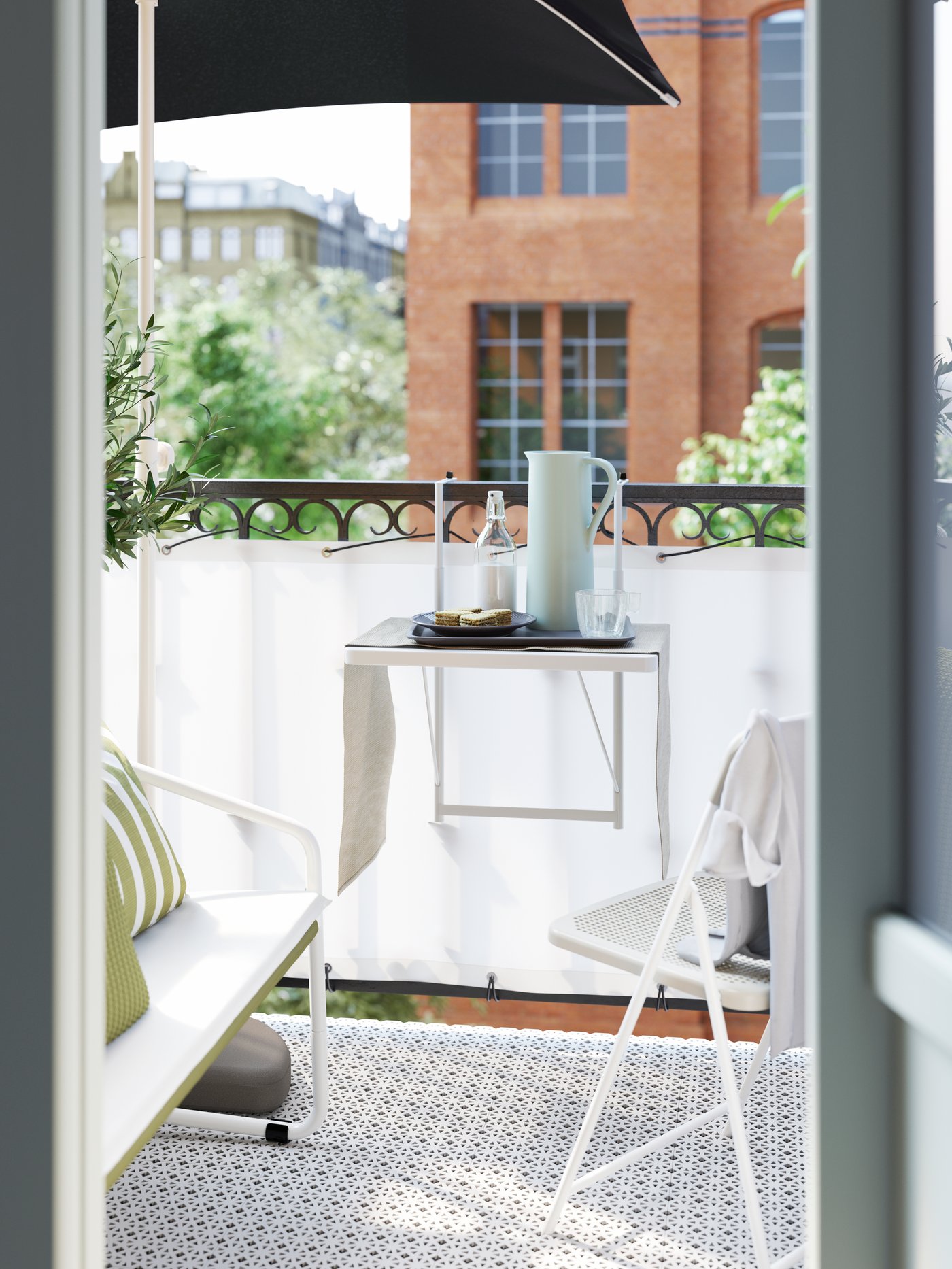 A small white balcony table hung on the balcony rail, with a pitcher, a plate of food and drinks on it.