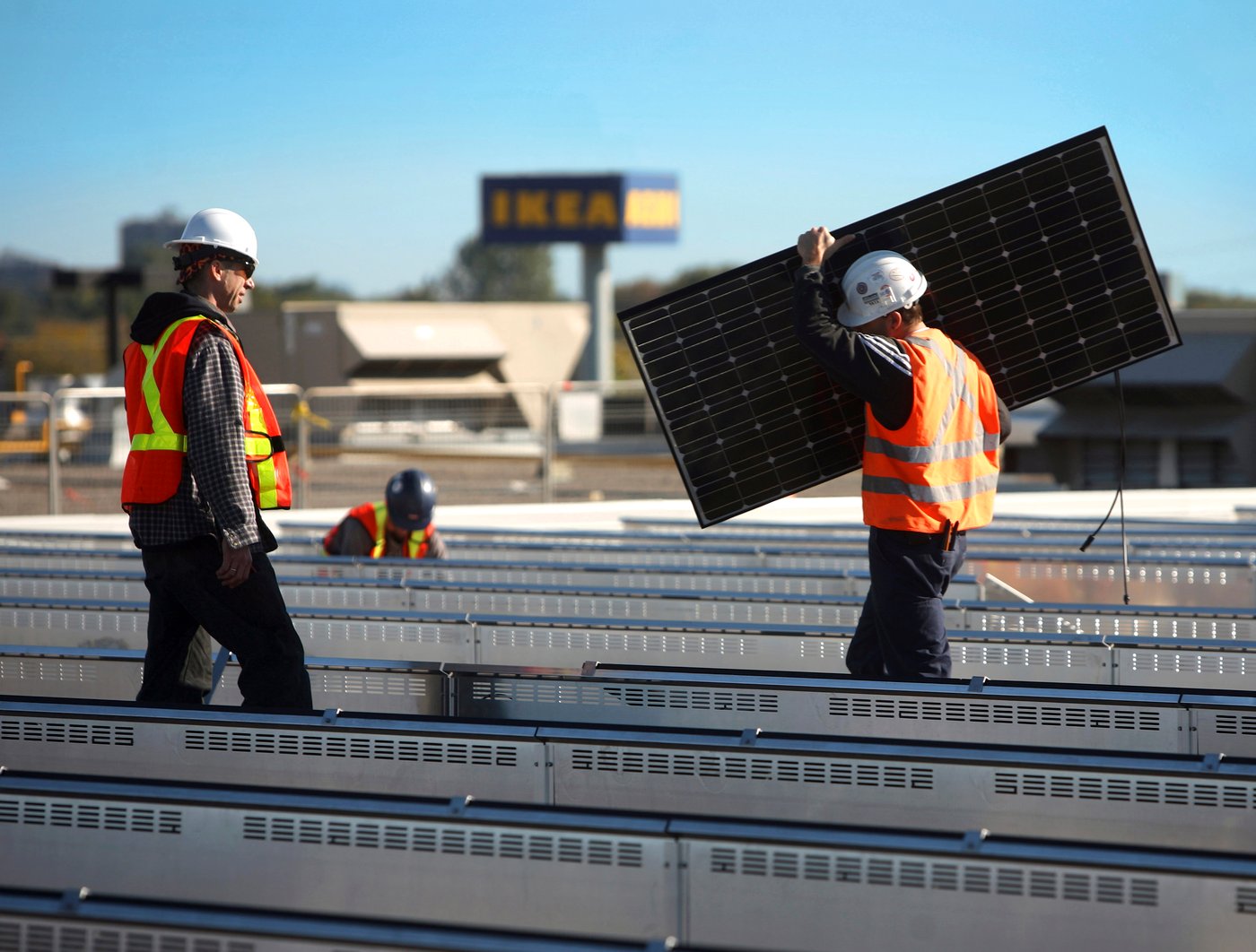 Mensen met veiligheidsvesten aan installeren zonnepanelen bij een IKEA winkel.