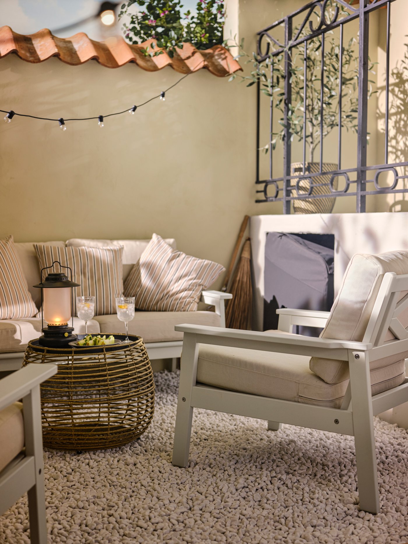 Es ist eine Sitzecke im Freien mit einem BONDHOLMEN 2er-Sofa, zwei BONDHOLMEN Armlehnstühlen und einem FÅLSKÄR Couchtisch auf einem weissen Teppich zu sehen.