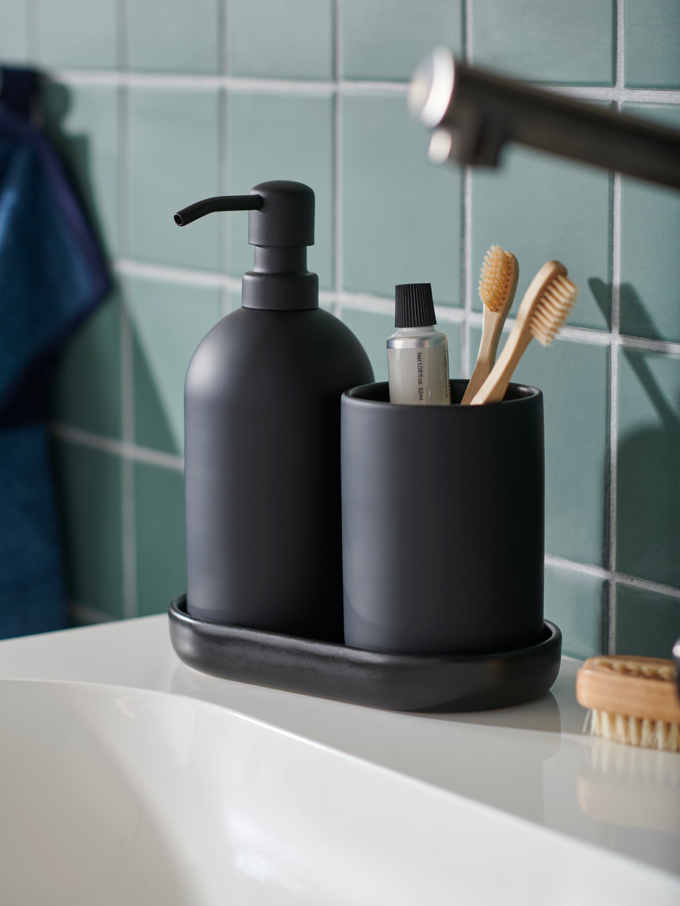 Set 3 unit perkakas bilik mandi buatan tembikar batu GANSJÖN yang diletakkan pada penjuru sink cuci tangan di dalam bilik mandi jubin berwarna hijau.