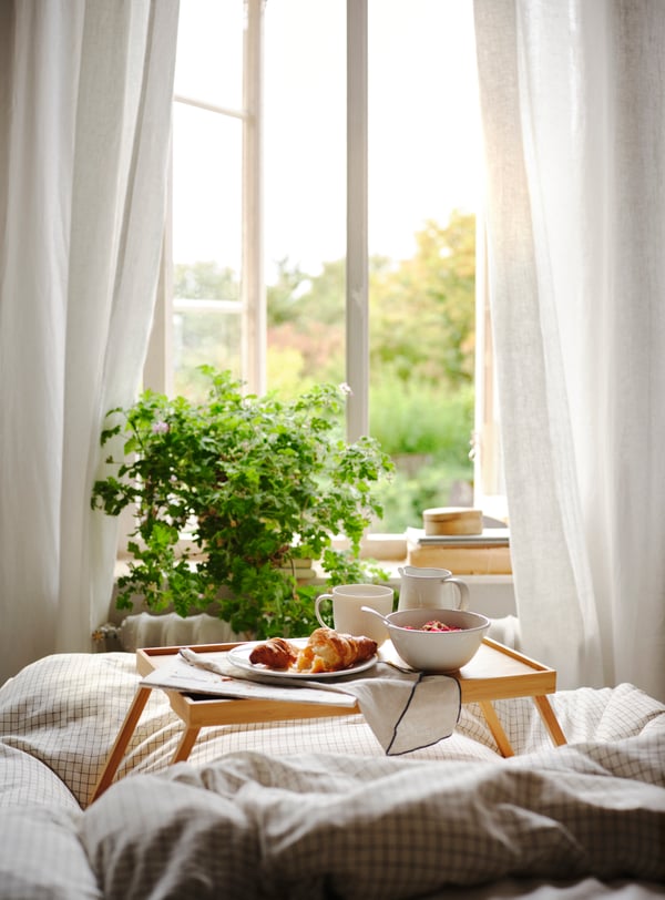Un letto con un vassoio alto contenente una colazione cucinata.