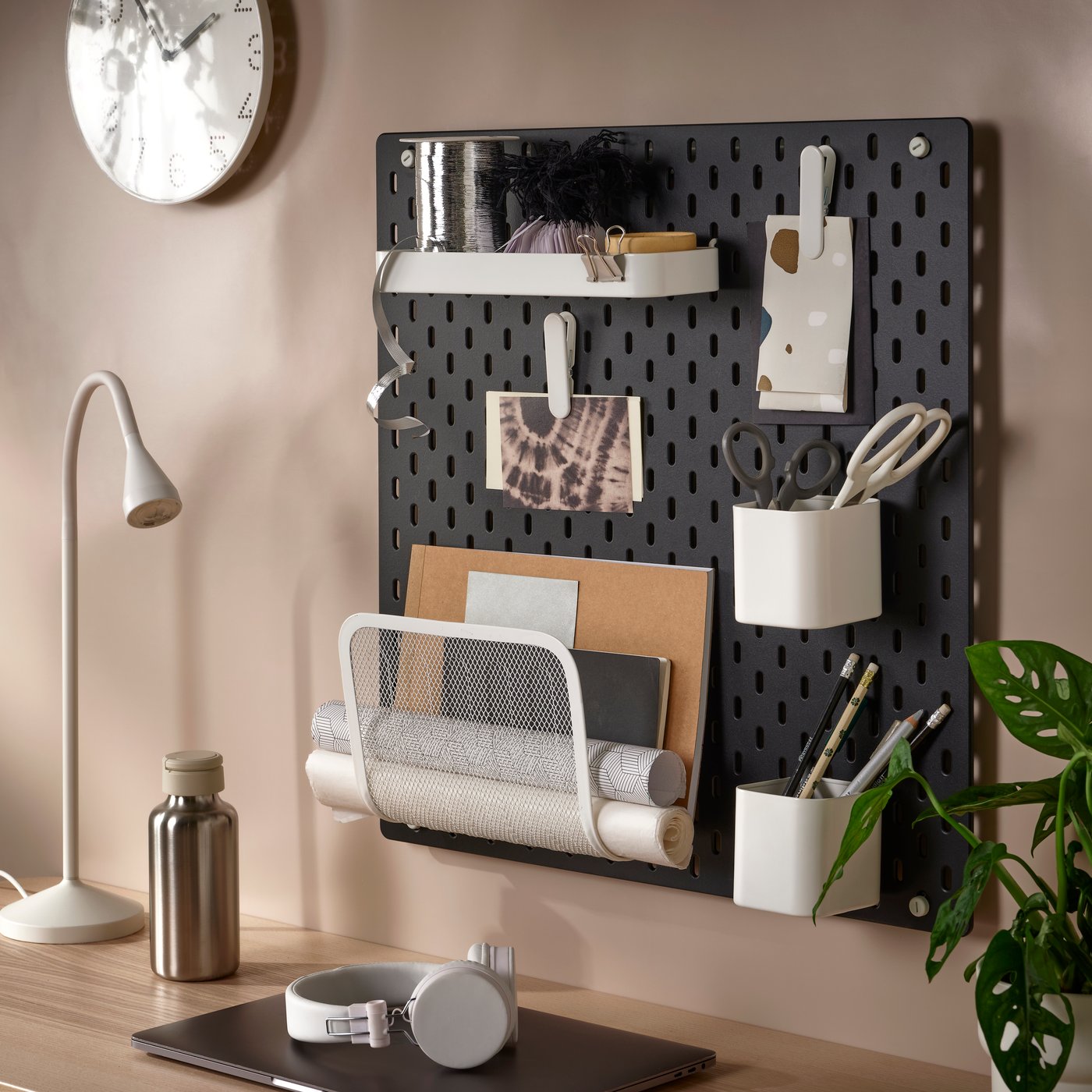 Espacio de estudio con escritorio de color café, con un organizador de pared de color negro una lampara de escritorio de color blanca.