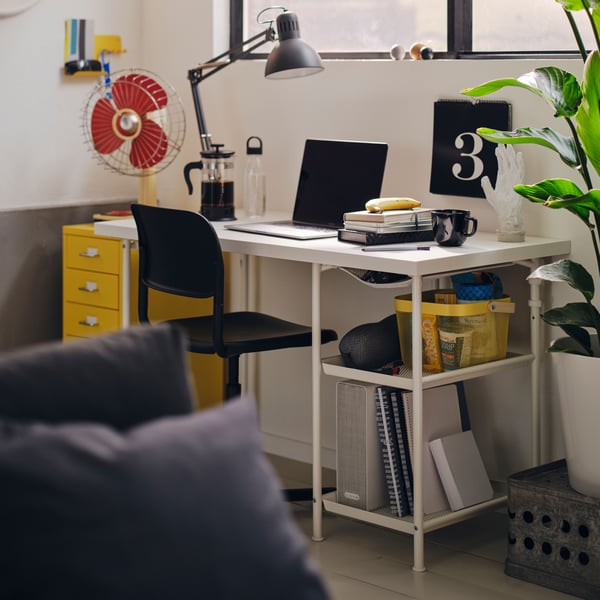 A vibrantly coloured space with a swivel chair and a slim-legged table in the middle, placed on a geometric-pattern rug.