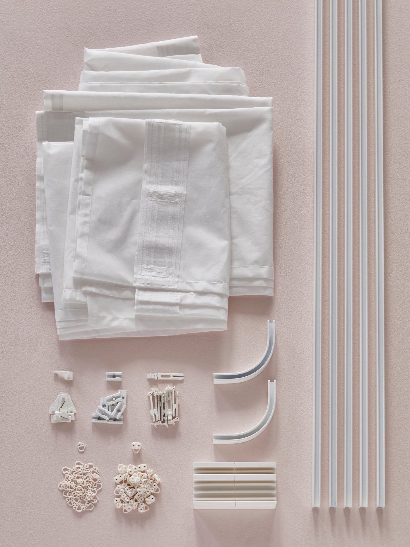 Rails, a cutting box, corner pieces and other items from the VIDGA curtain track system, and white curtains.