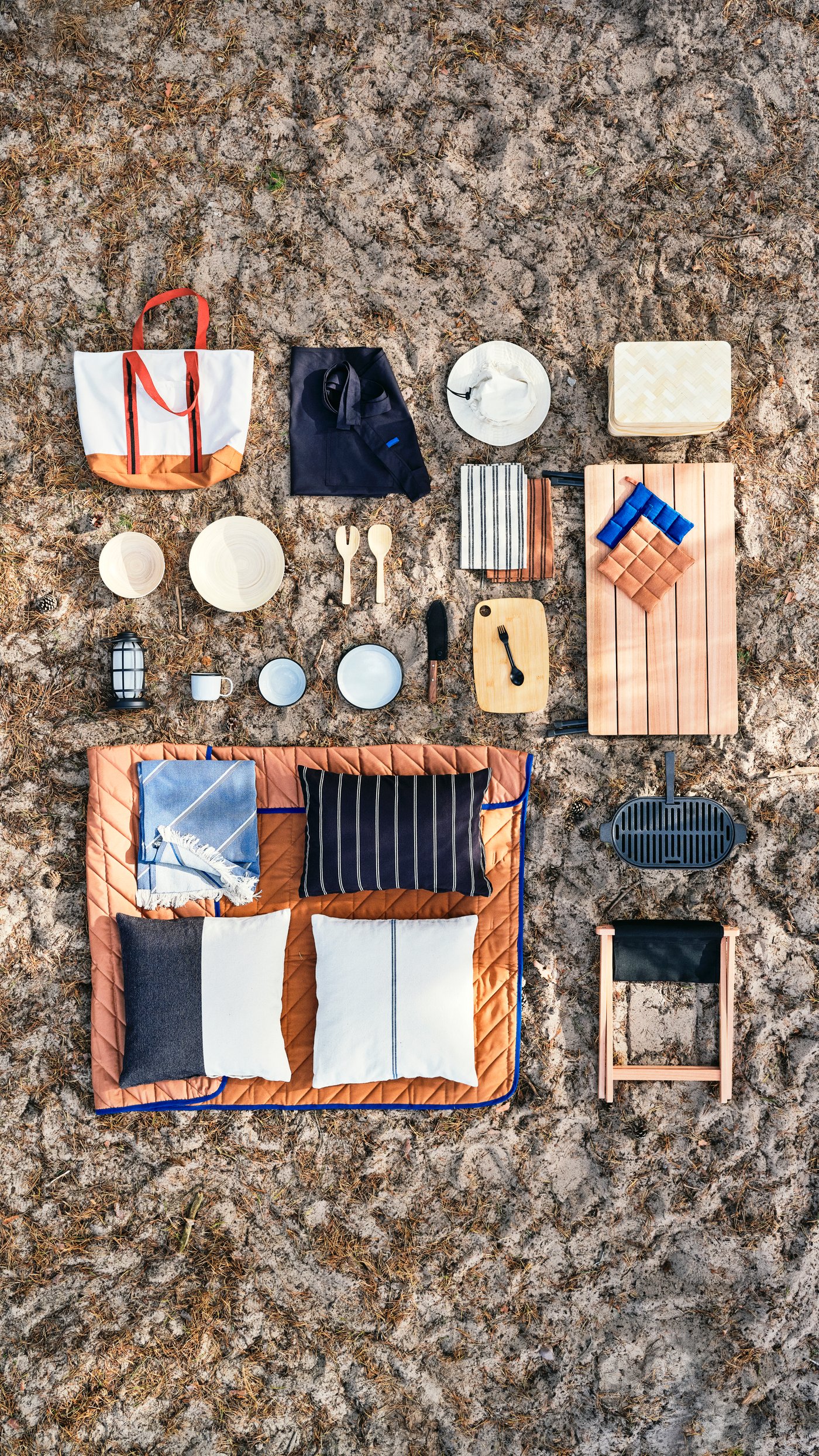 On a sandy ground, the products of the whole SOLUPPGÅNG collection is presented in a neat flatlay grid.