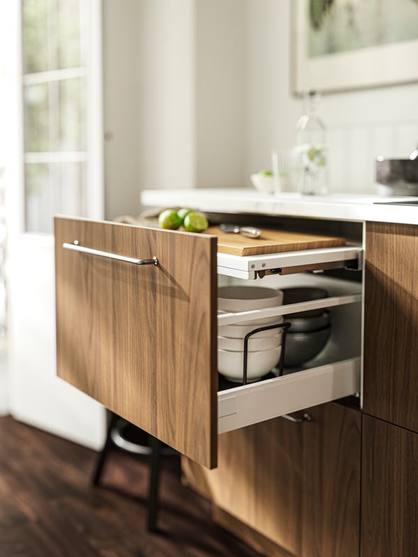 Un plan de travail coulissant ouvert avec des façades TISTORP, sur lequel se trouvent une planche à découper, un couteau et des limes.