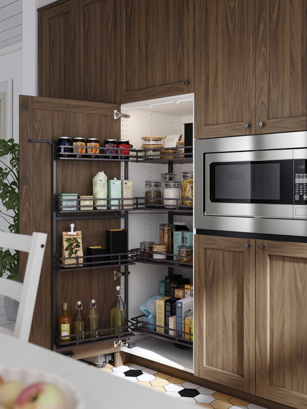 A high kitchen cabinet containing an UTRUSTA pull-out larder filled with different types of food in containers and bottles.