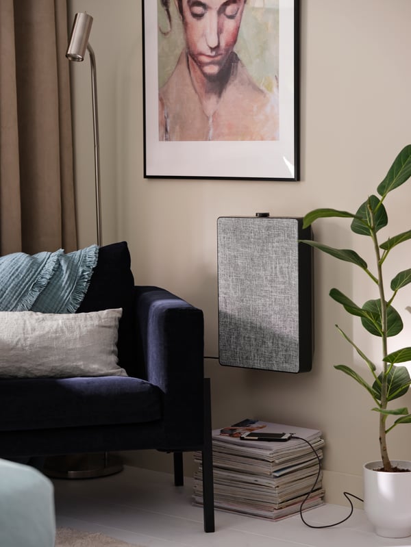 An armchair, floor/reading lamp, a framed artwork, an air purifier hung on the wall, a charging mobile phone.