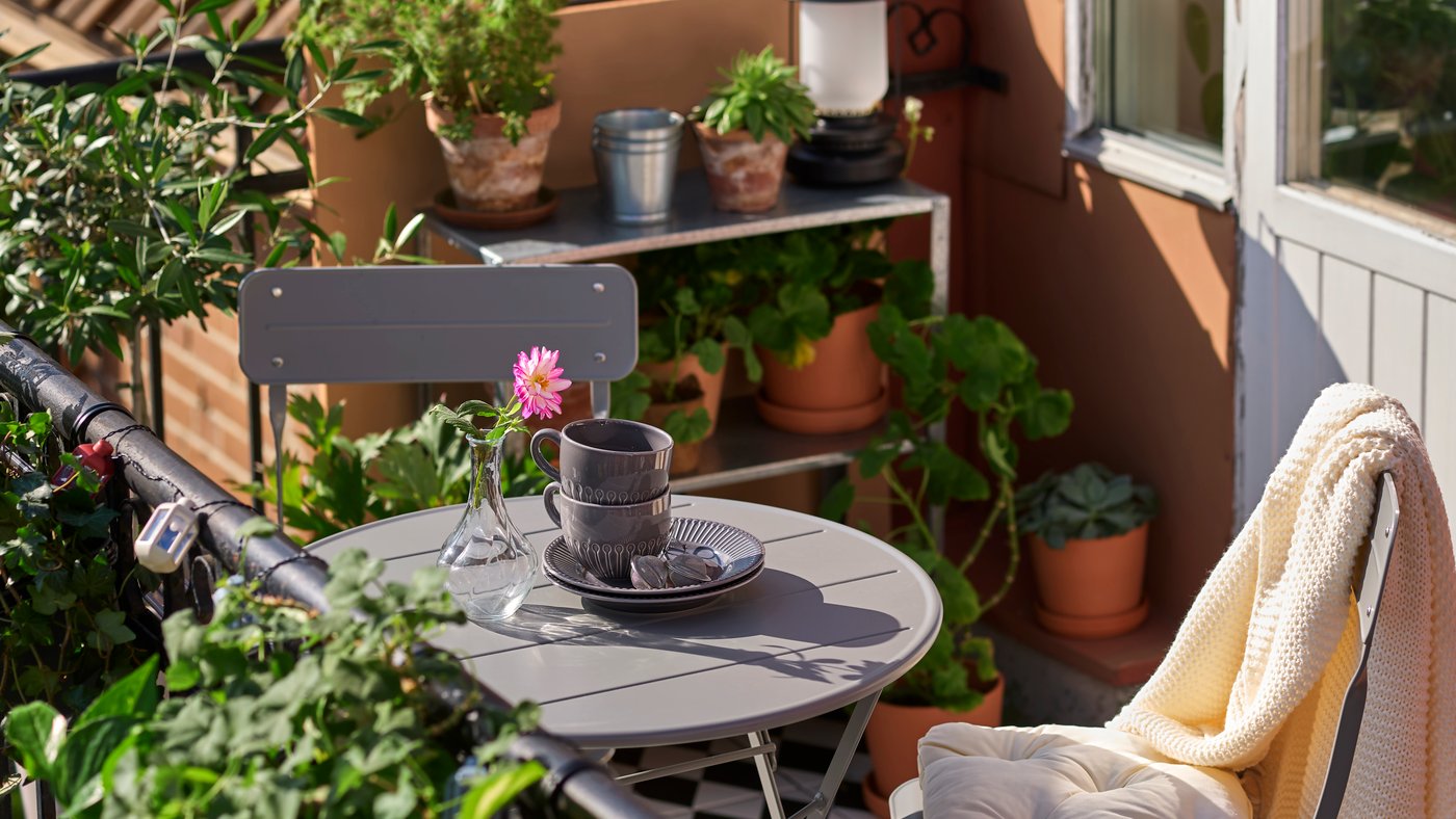 Bild på en balkong med ett SUNDSÖ caféset och en HYLLIS hylla med växter och odlingar på.