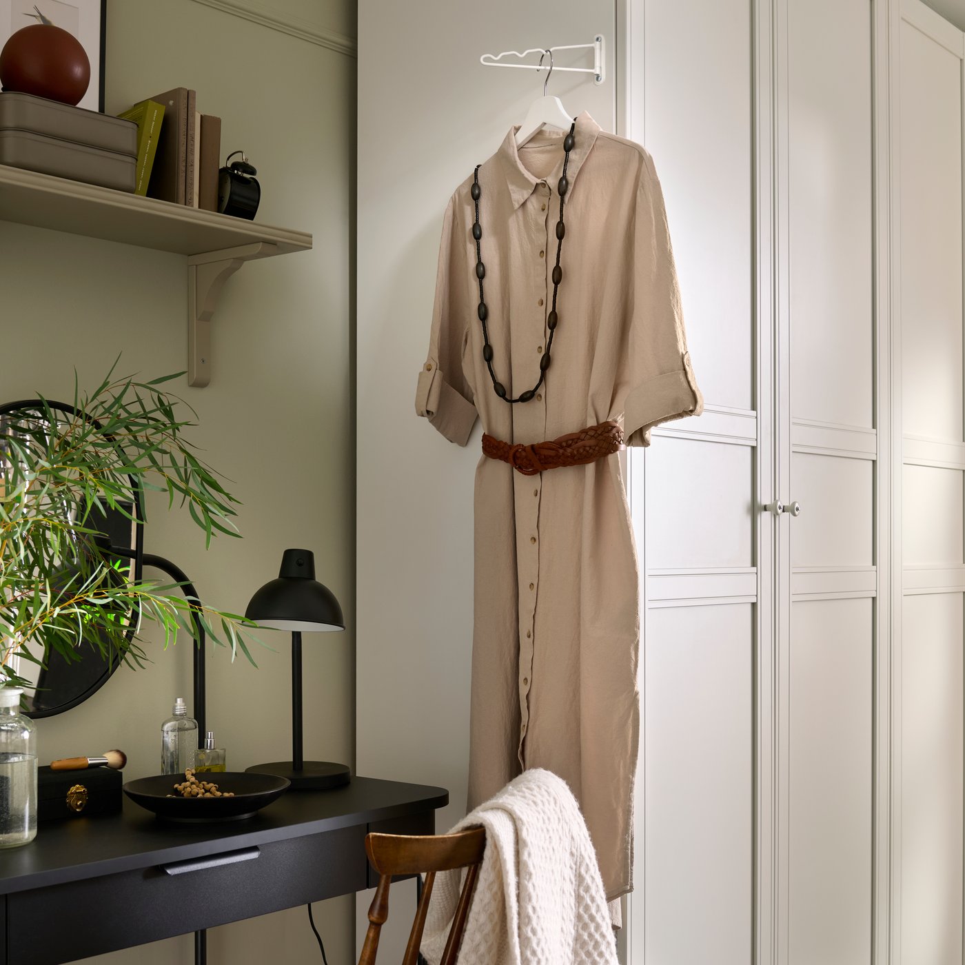 A white PAX wardrobe with a KOMPLEMENT valet attached to the side and a beige dress hanging on it.