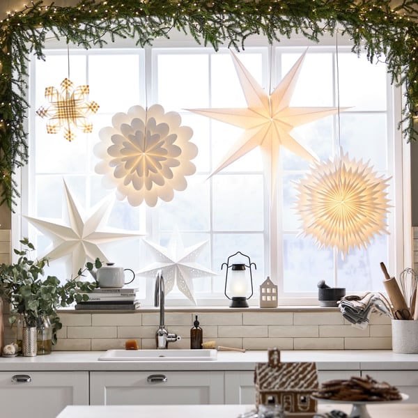 View of kitchen window at Christmas decorated with STRÅLA decorative lighting including star and flower shaped pendants.