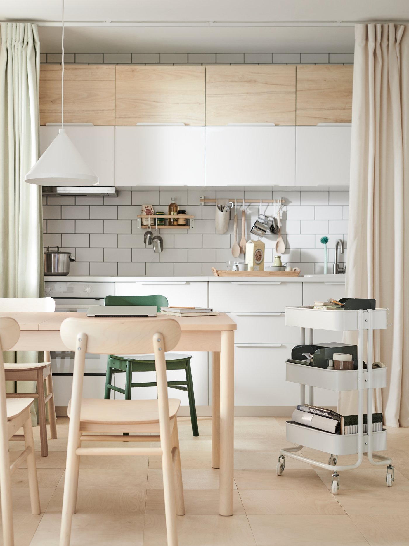 Una cocina con mesa de comedor adentro y los muebles de cocina combinan blanco y madera.