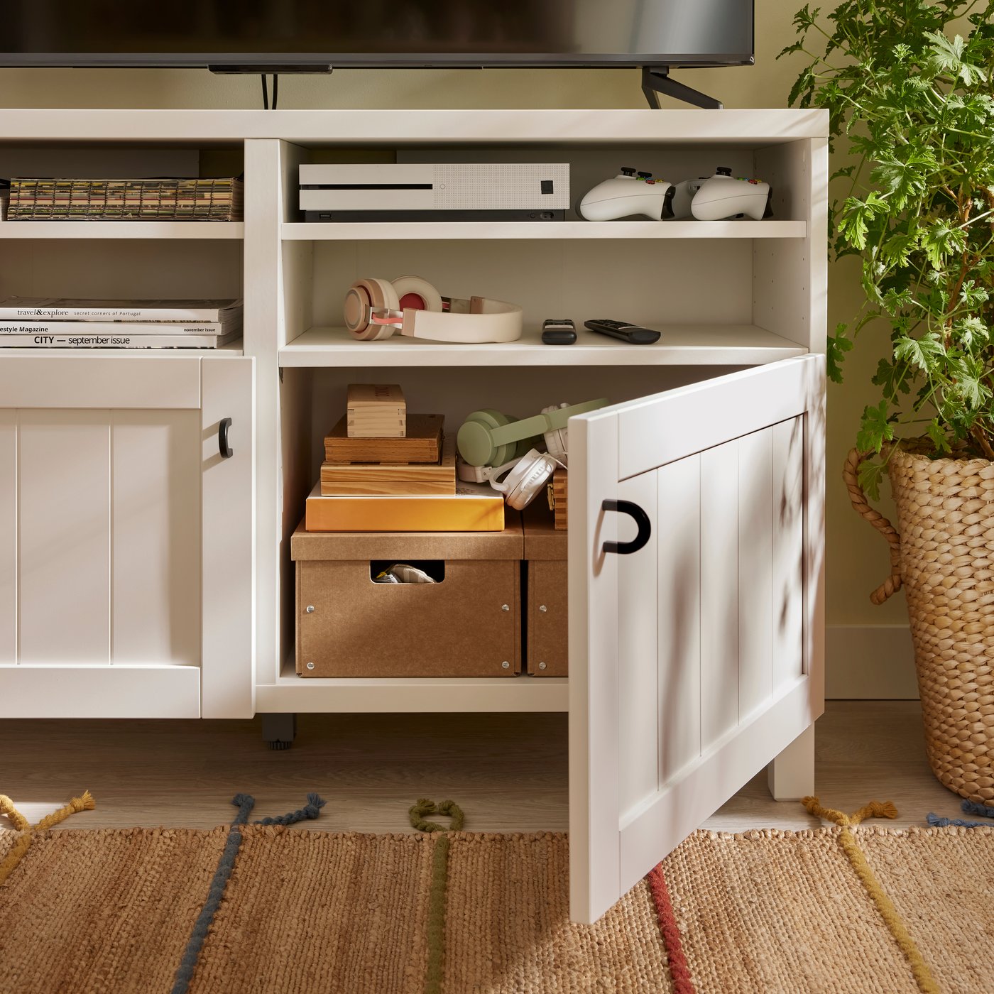 GÄRDESGÅRD storage boxes with lid stand on a shelf of a white BESTÅ TV bench with PIPMAKARE doors. One door is open.
