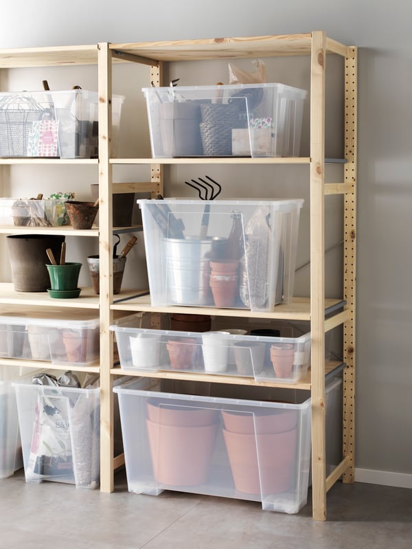 A bright space with IVAR shelving units hold multiple large SAMLA transparent-plastic boxes, in turn holding gardening items.